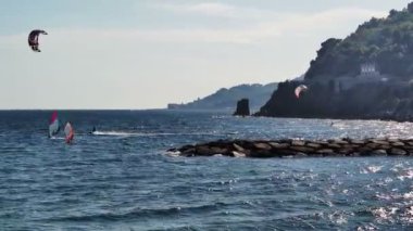 Ligurian kıyılarında rüzgar sörfü yapan insanlar var.