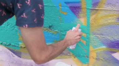 Sprey kutularla resim çizen sanatçı.