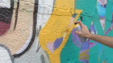 Sprey kutularla resim çizen sanatçı.