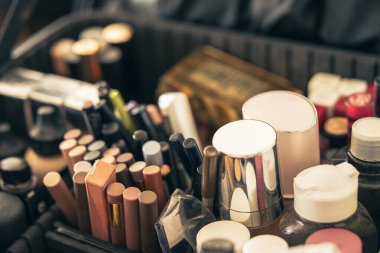 Detail of professional cosmetics inside a beauty case, with lipsticks, pencils, creams, and foundation for makeup artists