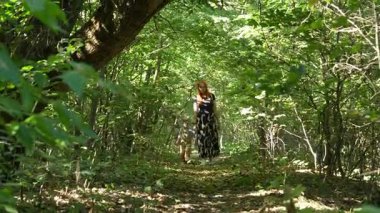 4K 50fps videosunda genç bir kadın ve küçük bir çocuğun orman yolunda birlikte yürüdüğünü görüyoruz. Yeşillik ve sakin atmosferli aile anları.