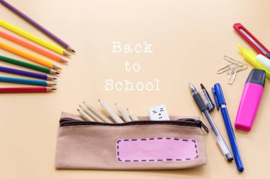 Okulun arka planına hoş geldiniz. Renkli renkli kalem ve kırtasiye çantası.