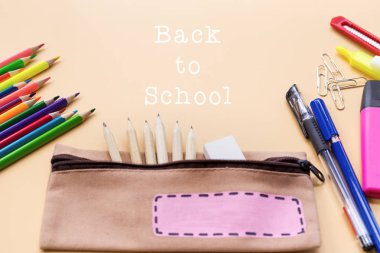 Okulun arka planına hoş geldiniz. Renkli renkli kalem ve kırtasiye çantası.