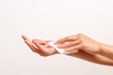 Kadın ellerini beyaz yumuşak mendil kağıdıyla temizliyor. Beyaz bir arka planda izole edilmiş