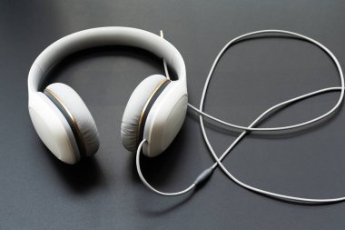 Siyah arkaplanda beyaz kulaklıklar var.