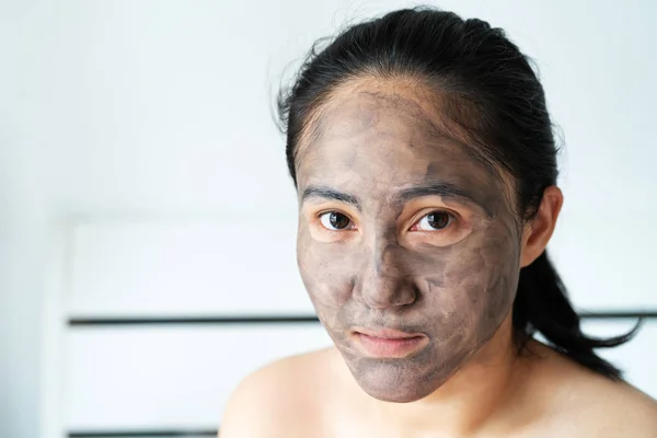 asia woman applied charcoal mask on her bare face