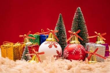 Noel konsepti. Altın zilli Noel hediyesi kutusu ve ağaç, çam kozalakları, kırmızı arka planda kırmızı ve beyaz top