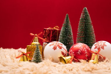 Noel konsepti. Altın zilli Noel hediyesi kutusu ve ağaç, çam kozalakları, kırmızı arka planda kırmızı ve beyaz top