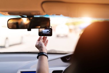 Front camera car recorder, woman set video recorder next to a rear view mirror clipart