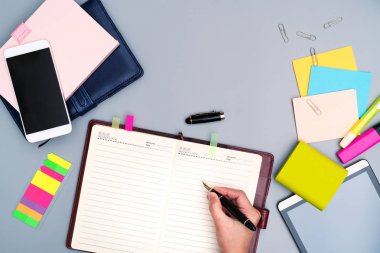 El yazısı üstünde defter ofis aksesuarları ile çevrili. Üstten görünüm çalışma masası. Smartphone, kitap, güç banka, kalem, planlayıcısı ve kağıt