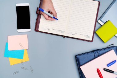 El yazısı üstünde defter ofis aksesuarları ile çevrili. Üstten görünüm çalışma masası. Smartphone, kitap, güç banka, kalem, planlayıcısı ve kağıt