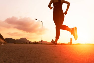 Sporcu kadın yolda koşuyor. Gün batımında spor yapan kadın antrenmanı