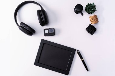 Mockup, fotoğraf çerçevesi, eylem kamera, kulaklık, kalem ve kaktüs, beyaz arka planda siyah nesne