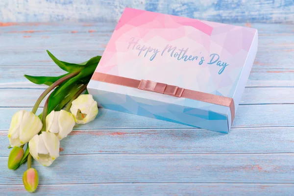 Feliz concepto del día de la madre. Caja de regalo y flor en mesa de madera — Foto de Stock