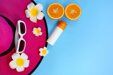 Güzel yaz tatili, plaj aksesuarları, güneş gözlükleri, şapka ve güneş kremi mavi arka planda.