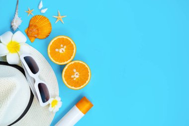 Güzel yaz tatili, plaj aksesuarları, güneş gözlükleri, şapka, turuncu, güneş kremi ve mavi arka planda deniz kabukları.