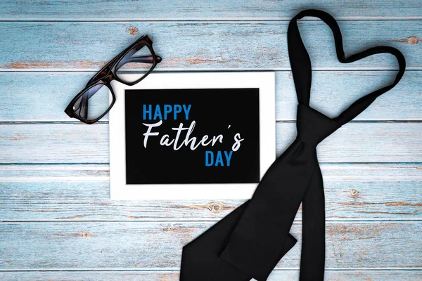 Tarjeta de felicitación feliz día de los padres con corbata y gafas en la mesa de madera, estilo laico plano — Foto de Stock