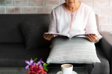 evde kahve fincanı ile bir kitap okuma yaşlı kadın