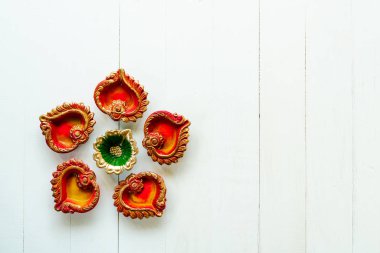Mutlu Diwaliler - Dipavali sırasında Clay Diya lambaları yandı, Hindu ışık festivali kutlaması. Beyaz ahşap arka planda renkli geleneksel gaz lambası diya