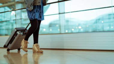 Bavullu bir yolcu, havaalanı terminalinde hava yolculuğu için valiz ve yolcu taşıyor.