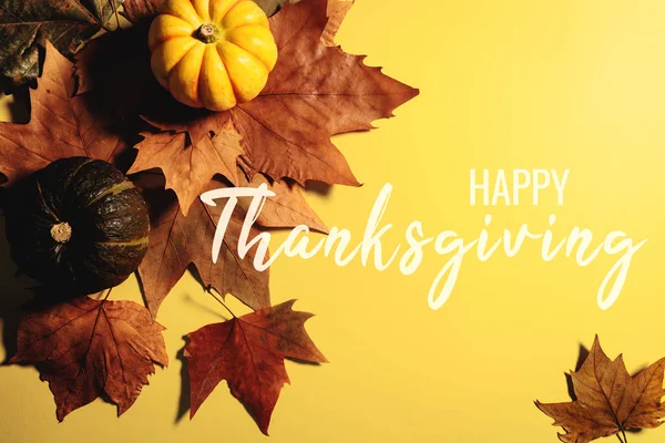 Feliz Día de Acción de Gracias con hojas de arce y calabaza sobre fondo amarillo — Foto de Stock