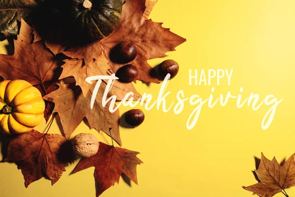 Feliz Día de Acción de Gracias con hojas de arce, nuez y calabaza sobre fondo amarillo — Foto de Stock