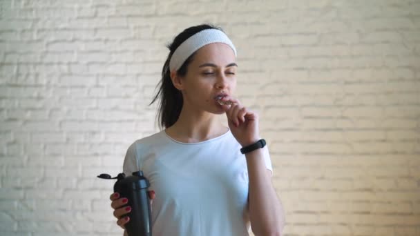 Atractiva hermosa mujer deportiva come barra de proteína y bebidas batido de proteína — Vídeo de stock