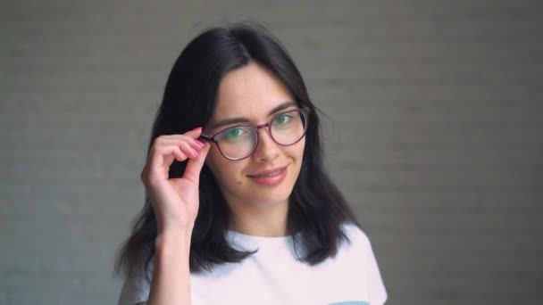Portrait d'une jeune femme brune en lunettes et accolades sur ses dents souriant à la caméra . — Video