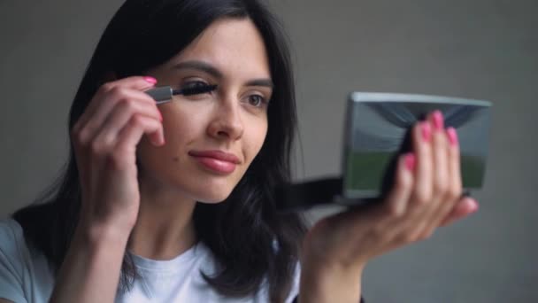 Beauté adolescente appliquant mascara maquillage et s'admirant dans le miroir. Belle étudiante se regardant dans le miroir à la maison et appliquer maquillage . — Video