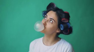 Kabarcıklar chromakey, yeşil bir arka plan üfleme kızla curlers kafa ve sakız,.