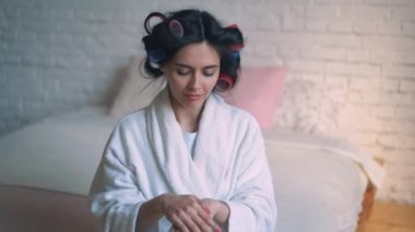 Genç bir kız, bir ev kadını olarak curlers, eller cilt için bakım. Güzellik Spa kadın portre ile mükemmel cilt. güzel esmer