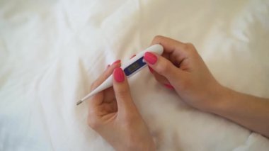 Kız yatakta o bu sabah hastalandı ve en kısa zamanda yeniden elde etmek istiyor oturuyor. Genç kadın daha sonra daha iyi hissetmek için biraz ilaç alacak