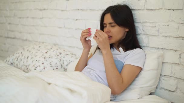 La chica está sentada en la cama se enfermó esta mañana y quiere recuperarse lo antes posible. Mujer joven tomará algún medicamento para sentirse mejor más tarde — Vídeo de stock