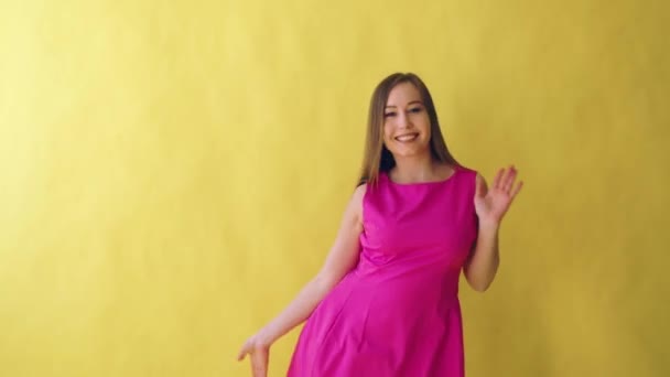 Jeune fille adulte attrayante en robe rose élégante sur fond jaune — Video