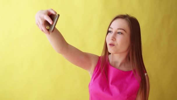 Молодая красивая леди, стоящая в изоляции на желтом фоне, делая селфи по телефону — стоковое видео
