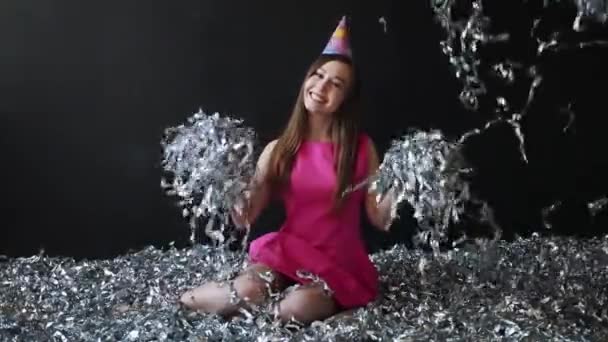 Glad ung kvinna i rosa klänning firar nyår eller födelsedag på svart bakgrund med konfetti — Stockvideo