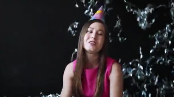 Šťastná dívka v růžových šatech slaví Nový rok nebo narozeniny na černém pozadí s konfety