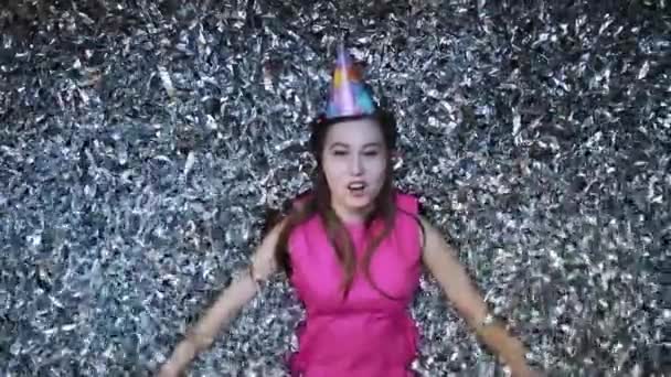 Happy young woman in pink dress celebrates New year or birthday on black background with confetti — Stock Video