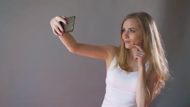 Hafif makyaj güzel kızla bir selfie gri bir arka plan üzerine alır..