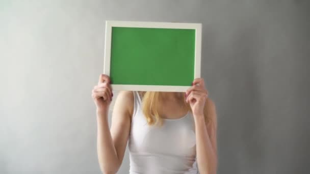 Aantrekkelijke vrouw toont groene sleutel kopie ruimte met het volgen van de punten. De plaat met een chromakey in de handen van het meisje — Stockvideo