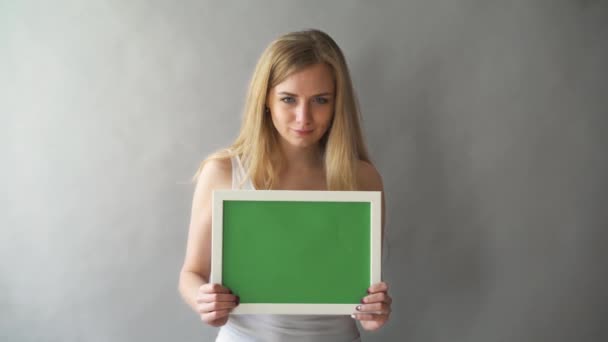 Ελκυστική γυναίκα δείχνει πράσινο κλειδί αντίγραφο χώρο με παρακολούθηση σημεία. Το πιάτο με ένα chromakey στα χέρια του το κορίτσι — Αρχείο Βίντεο