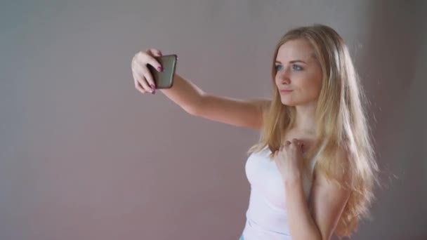 Krásná dívka s lehký make-up se selfie na šedém pozadí. — Stock video