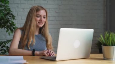 Görüntülü sohbet sahip laptop ile ofiste oturan genç iş kadını. Profesyonel erkek messenger uygulama gülümseyen tebrik gülen sallanan el ile konuşurken bilgisayar kullanarak.