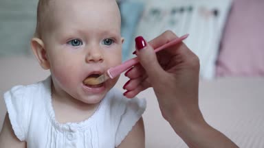 Anne bebek kızı bir kaşıkla besleme. Çok güzel çocuğunu evde anne verilmesi gıda
