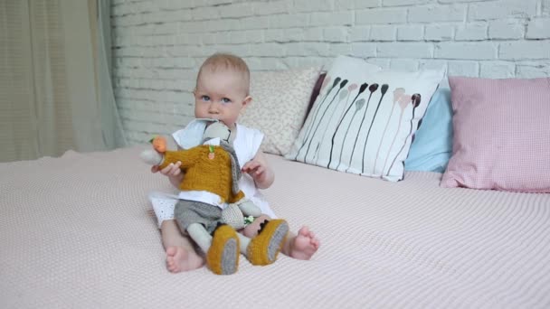 Krásná holčička hraje s Plyšová hračka králík na posteli. — Stock video