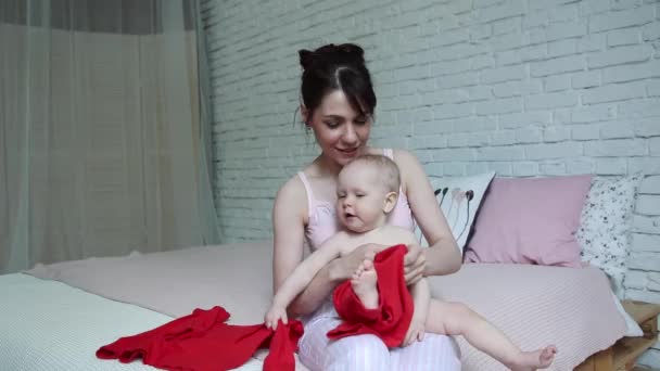 A mãe veste a criança. Mãe tentando vestir seu bebê — Vídeo de Stock