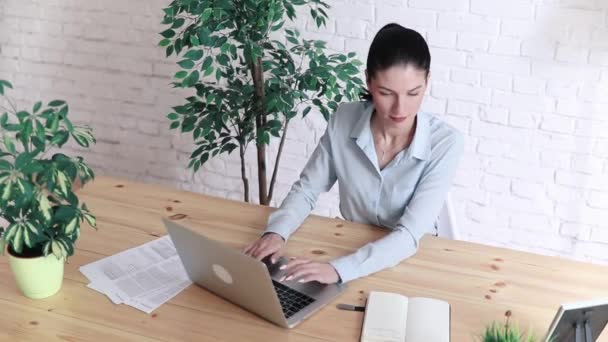 Portret van een mooie zakenvrouw maken van notities in een notitieblok. Houdt een pen, zittend op de werkplek — Stockvideo