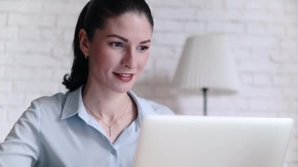 Jonge brunette zakenvrouw glimlachend achter bureau — Stockvideo