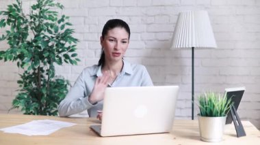 Söz ve sallayarak hippi kız gülümseyerek ve iş yerinde masada oturan bir dizüstü bilgisayar ile bir video aramasý sýrasýnda Merhaba. İnternette laptop üzerinden bir toplantısı neşeli iş kadını.