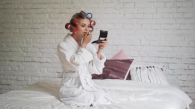 Sabahları banyo sonra curlers içinde güzel bir kız dudaklarını boyalar